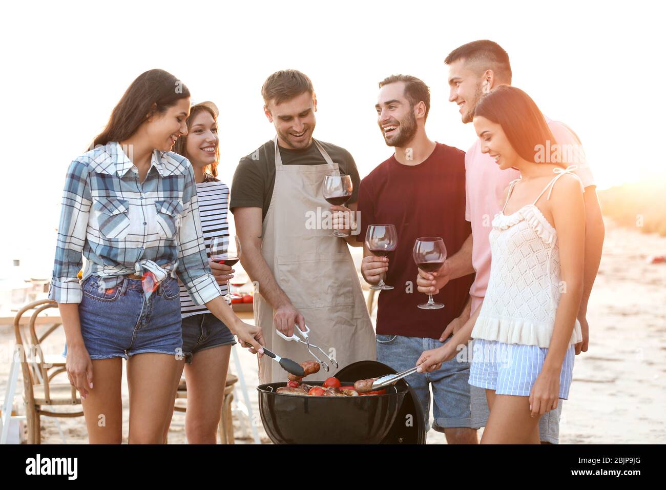 Junge Leute mit Grillparty am Strand Stockfoto