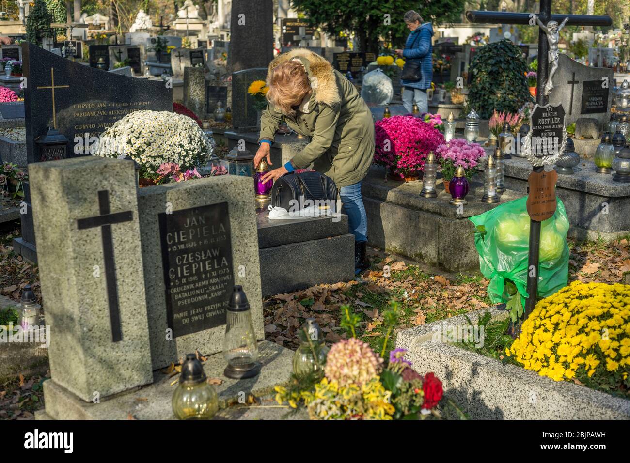 Eine Frau zündet eine Kerze auf dem Rakowicki Friedhof in Krakau, Polen 2019 an. Stockfoto