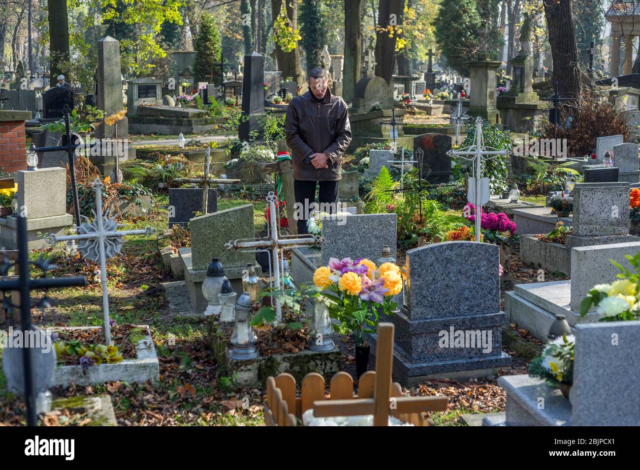 Ein Mann erinnert sich an seinen verstorbenen Angehörigen auf dem Rakowicki-Friedhof in Krakau, Polen im Jahr 2019. Stockfoto