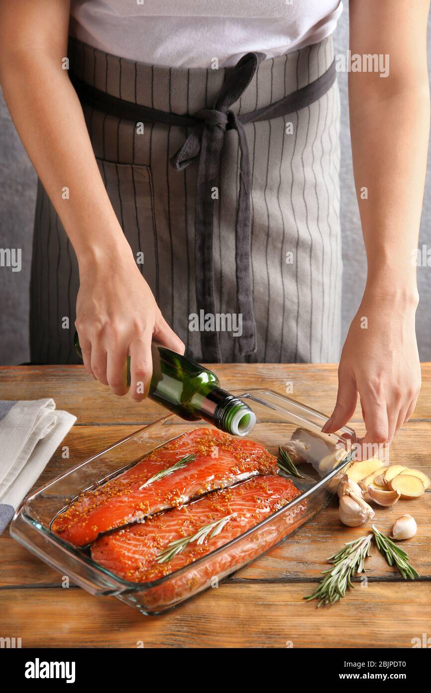 Frau bereitet Lachsfilet mit Marinade in Backform Stockfoto