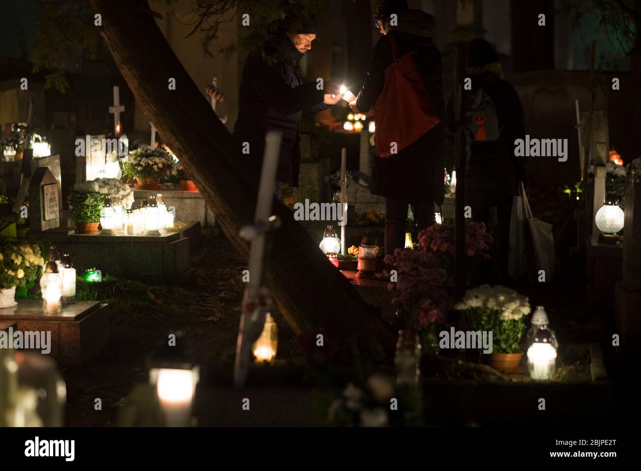 Menschen zünden eine Kerze auf dem Rakowicki Friedhof in Krakau, Polen 2019 an. Stockfoto