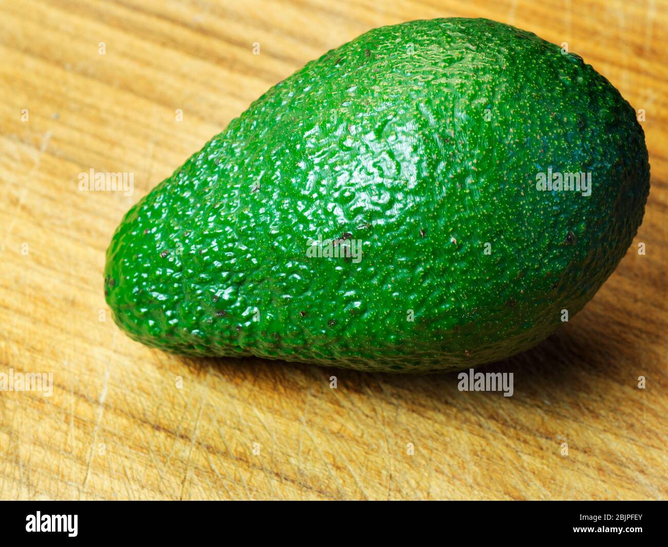 Eine einzelne Avocado-Frucht auf einem Holzhackbrett Stockfoto