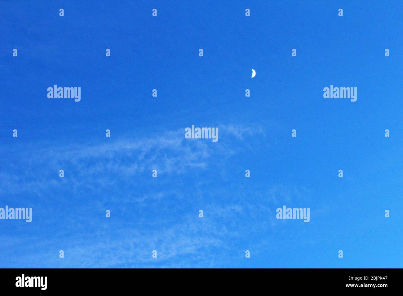 Ein Halbmond in einem klaren blauen Himmel in Manchester, England Stockfoto