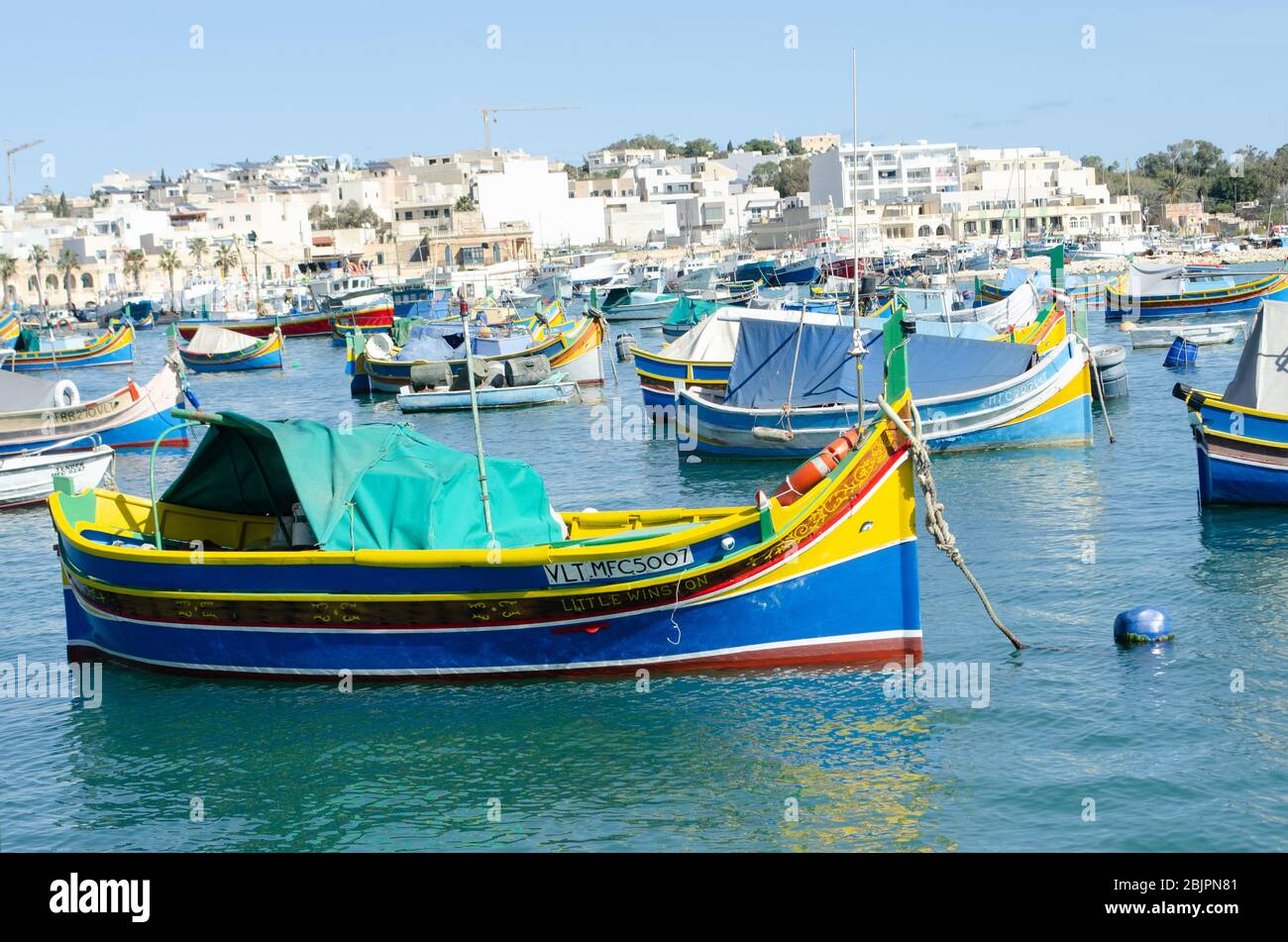 Marsaxlok Malta 9. Februar 2020: Malteserkorfer Marsaxlokk mit traditionellem bemaltem Boot im Vordergrund Stockfoto