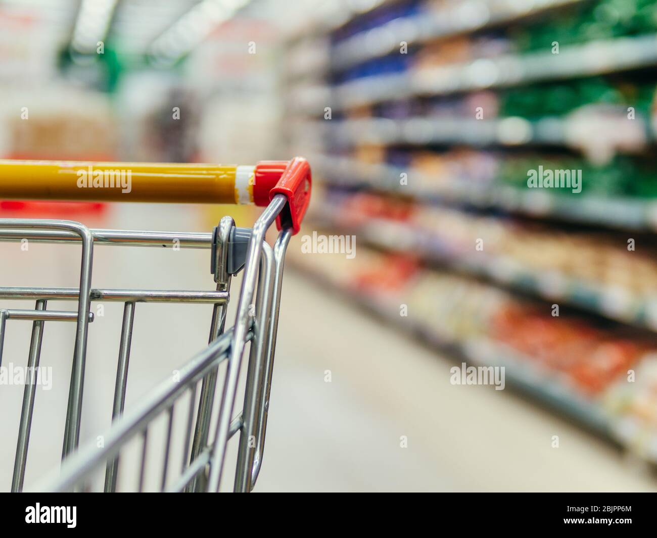 Warenkorb im Supermarkt. Teil der Einkaufswagen im Supermarkt Gang. Verschwommen Regale im Supermarkt und Trolley. Kopieren Sie Platz für Text oder Design. Stockfoto