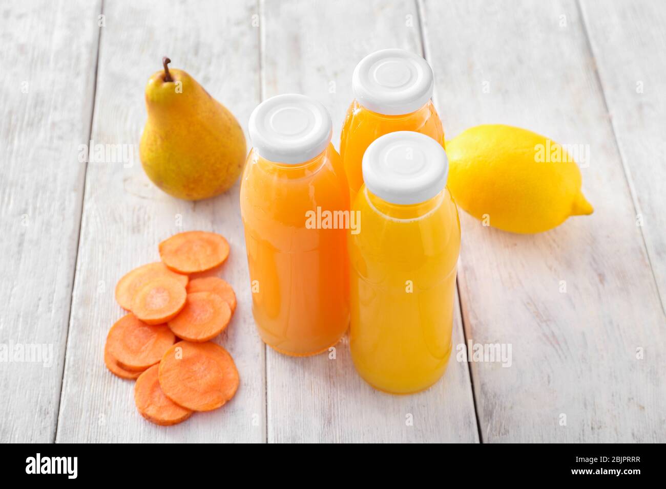 Flaschen mit Obst und Gemüsesäften auf Holztisch Stockfoto