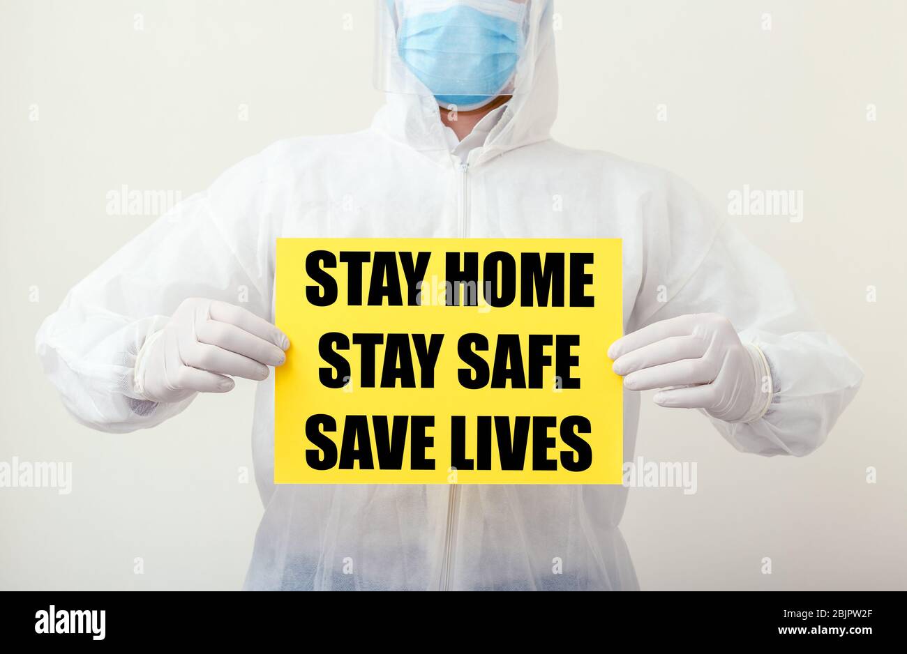 Stay Home Stay Safe Save Lives Text auf gelbem Warnschild in den Händen von Ärzten. Coronavirus, Covid-19 Selbstquarantäne-Isolierung. Medizin, Gesundheitswesen Stockfoto