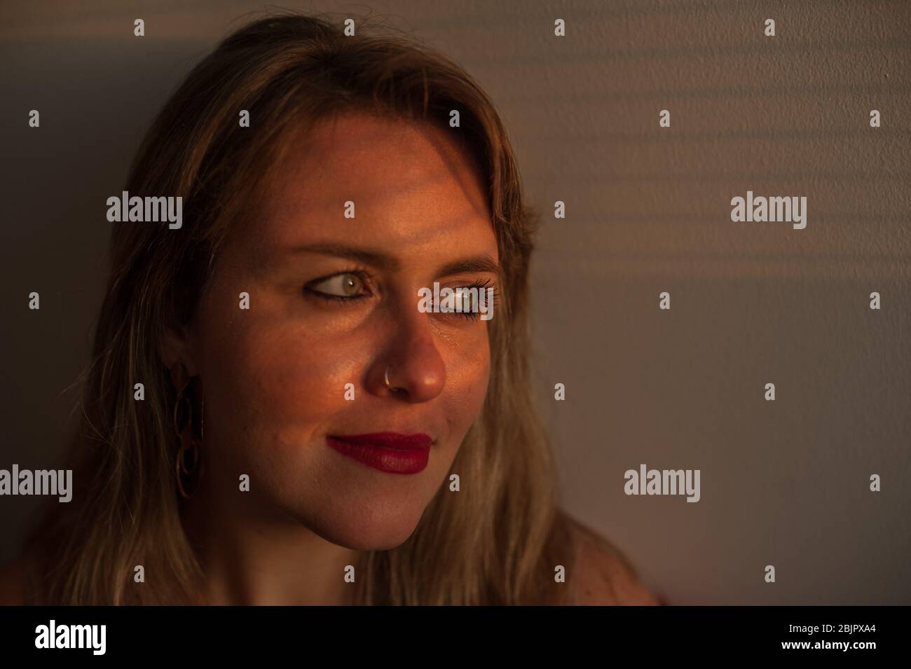 Junge natürliche blonde Frau, die mit Sonnenlicht über ihr Gesicht hinaus beleuchtet Stockfoto