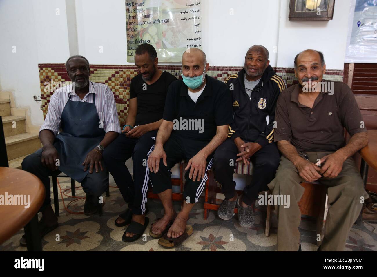 Tripolis, Libyen. April 2020. Haj Saleh Shushan (1. L) wird in seinem Restaurant mit Freiwilligen in Tripolis, Libyen, 29. April 2020 gesehen. Das Restaurant des Haj Saleh Shushan ist täglich im Zentrum der Hauptstadt Tripolis geöffnet und bietet den von den anhaltenden bewaffneten Konflikten und der verheerenden COVID-19-Pandemie geplagten Menschen kostenlose Mahlzeiten an. ZU GEHEN MIT: "Feature: In Zeiten von Krieg und Pandemie, Tripoli Restaurant bietet kostenlose Mahlzeiten Leiden zu lindern" Kredit: Mohmad Arhoma/Xinhua/Alamy Live News Stockfoto