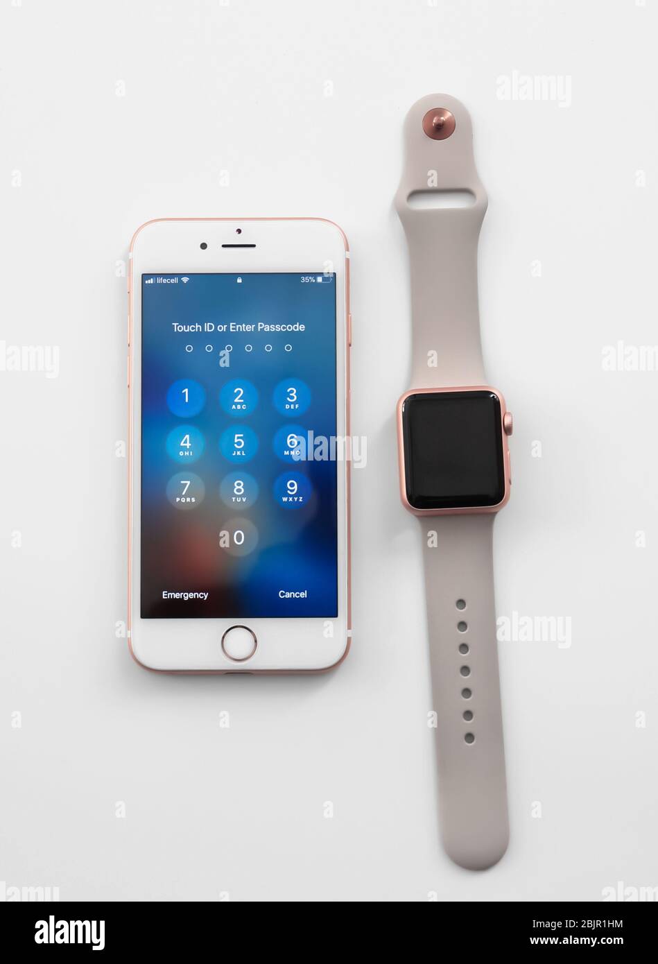 KIEW, UKRAINE - 17. OKTOBER 2017: Rose Gold iPhone 6S mit Ziffernblock zur Eingabe des Passcodes und Apple Watch auf weißem Hintergrund Stockfoto