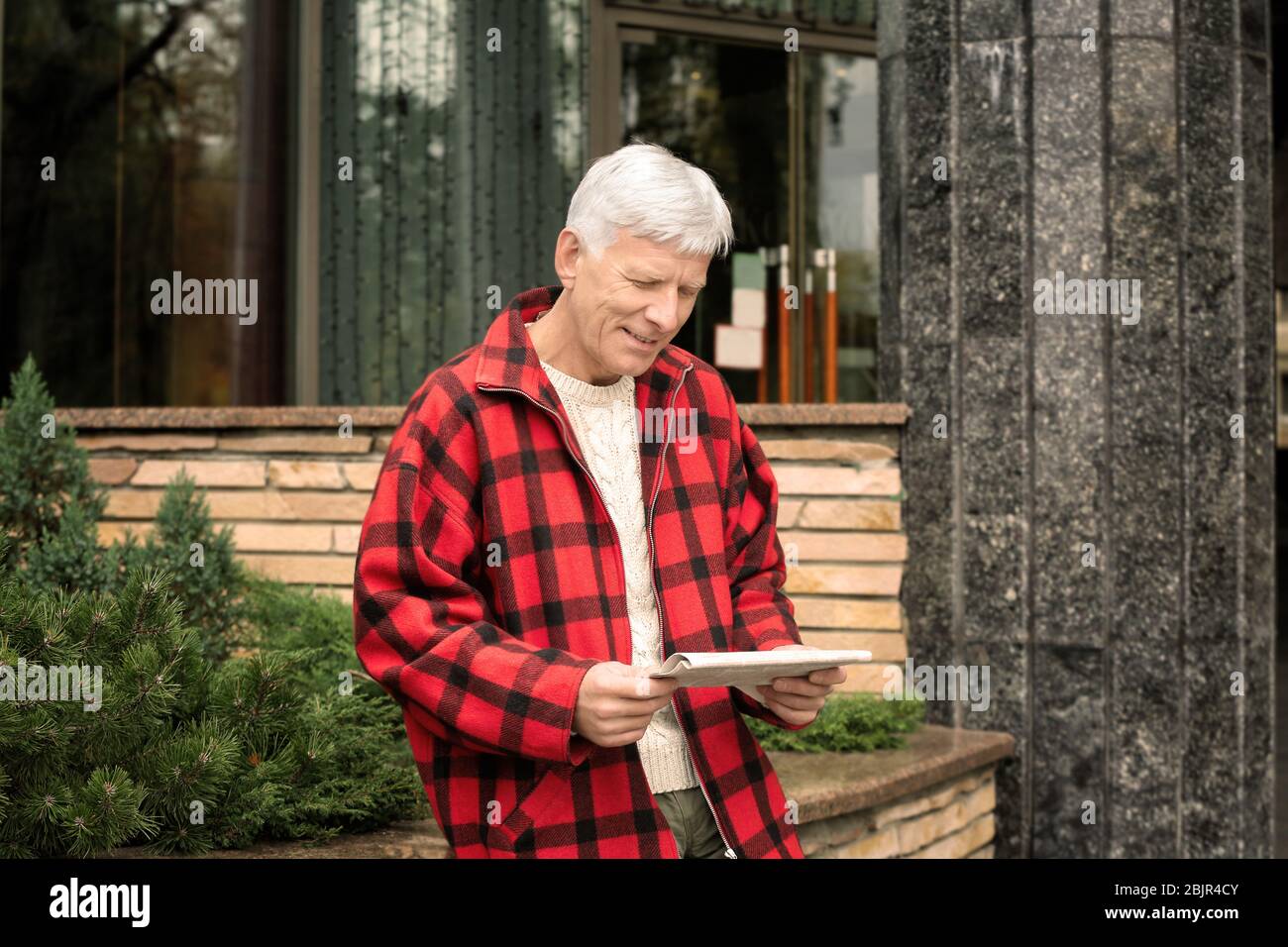 Schöner reifer Mann liest Zeitung im Freien Stockfoto