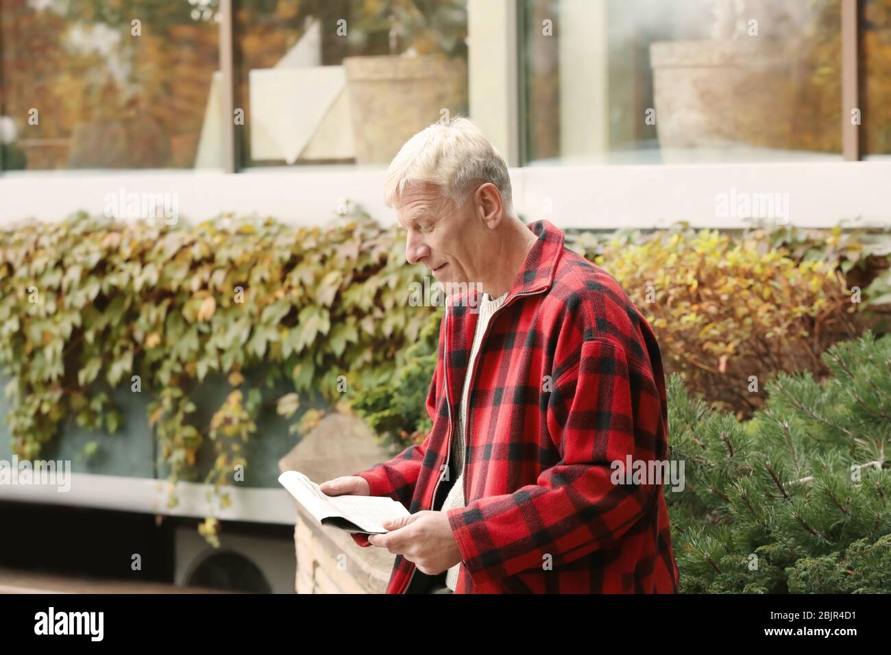 Schöner reifer Mann liest Zeitung im Freien Stockfoto