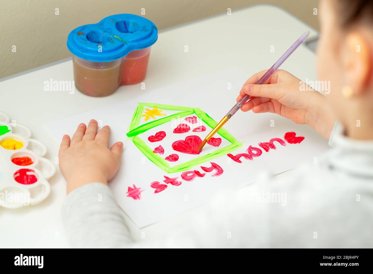 Kind zeichnet Herz im Haus auf weißem Blatt Papier mit Worten bleiben zu Hause. Stay Home Konzept. Stockfoto