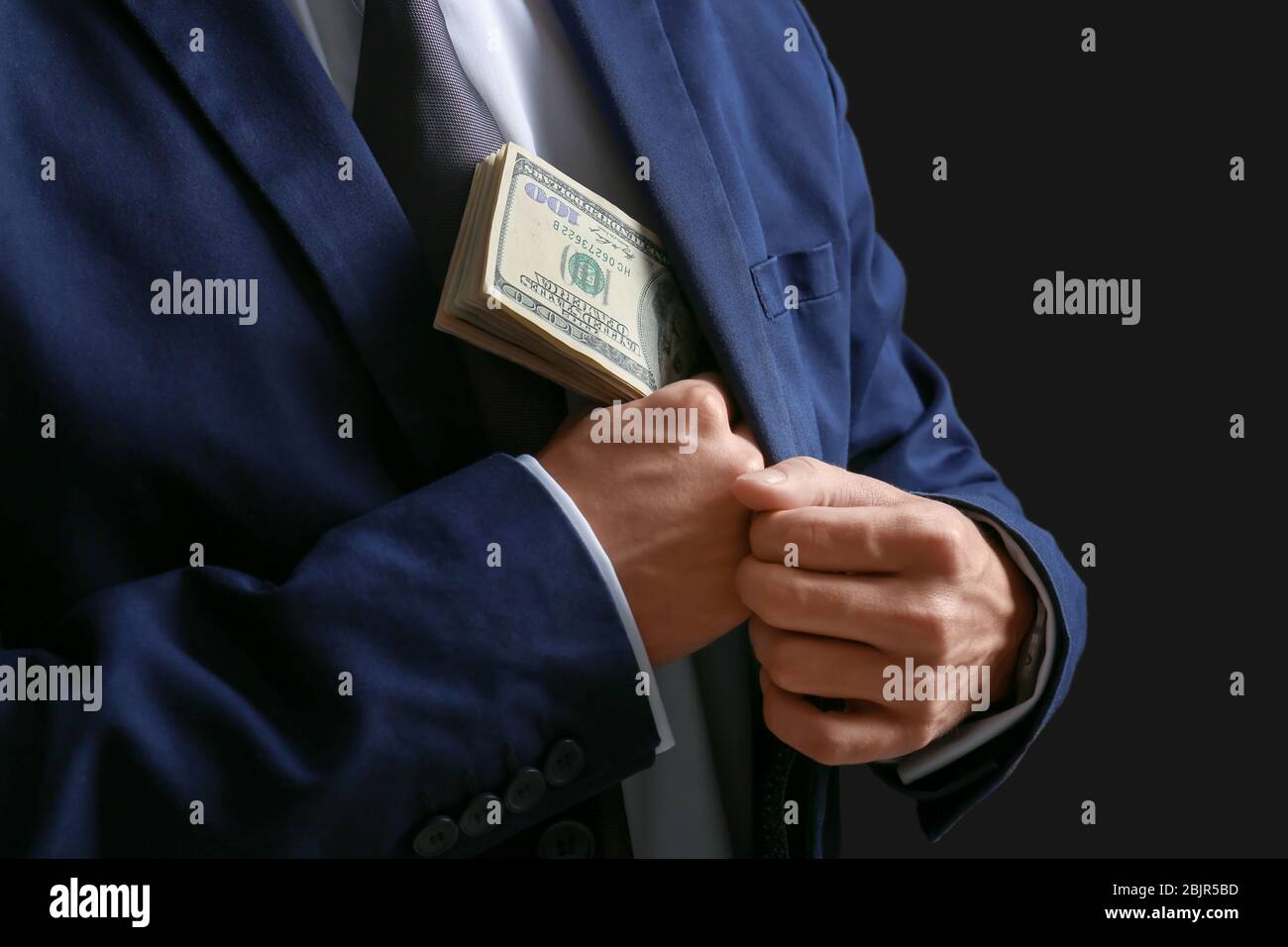 Mann in formellen Anzug, Geld in die Tasche auf dunklem Hintergrund, Nahaufnahme Stockfoto