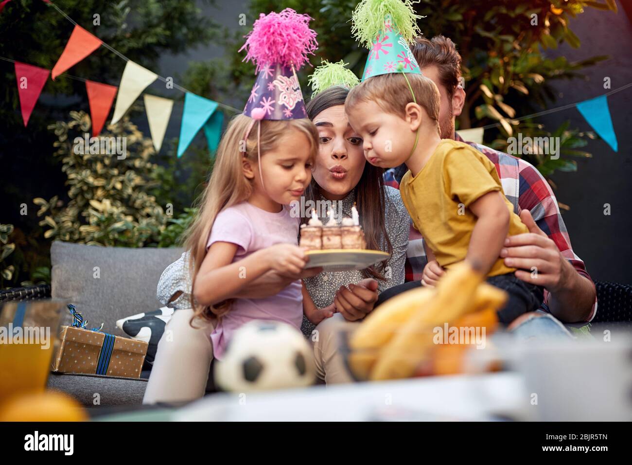 Versammelt junge Familie bläst Geburtstagskerzen zusammen. Geburtstag, Zweisamkeit Stockfoto