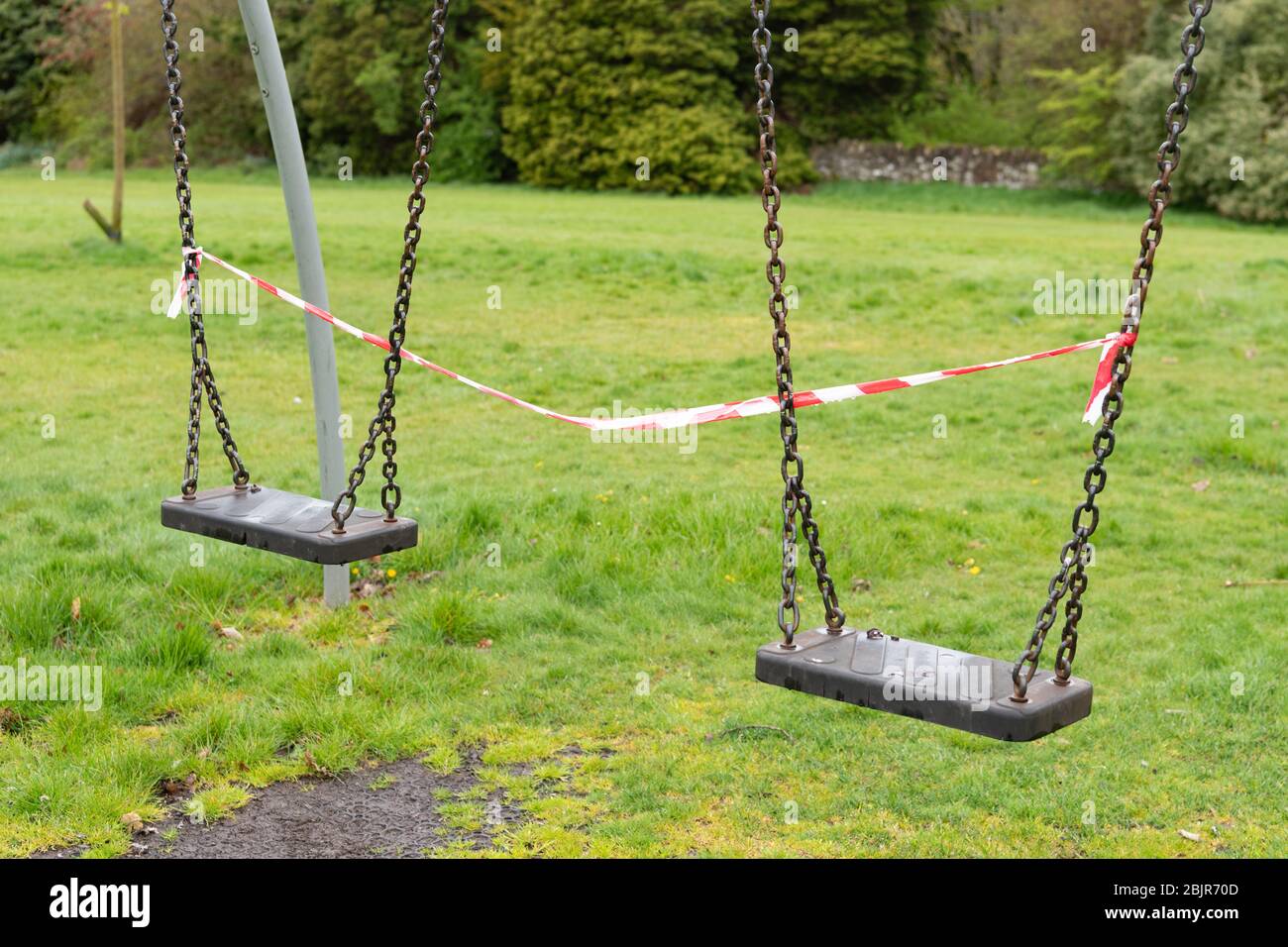 Spielpark während der Coronavirus-Pandemie geschlossen - zwei Schaukeln mit rotem und weißem Klebeband abgeklebt, Schottland, Großbritannien Stockfoto