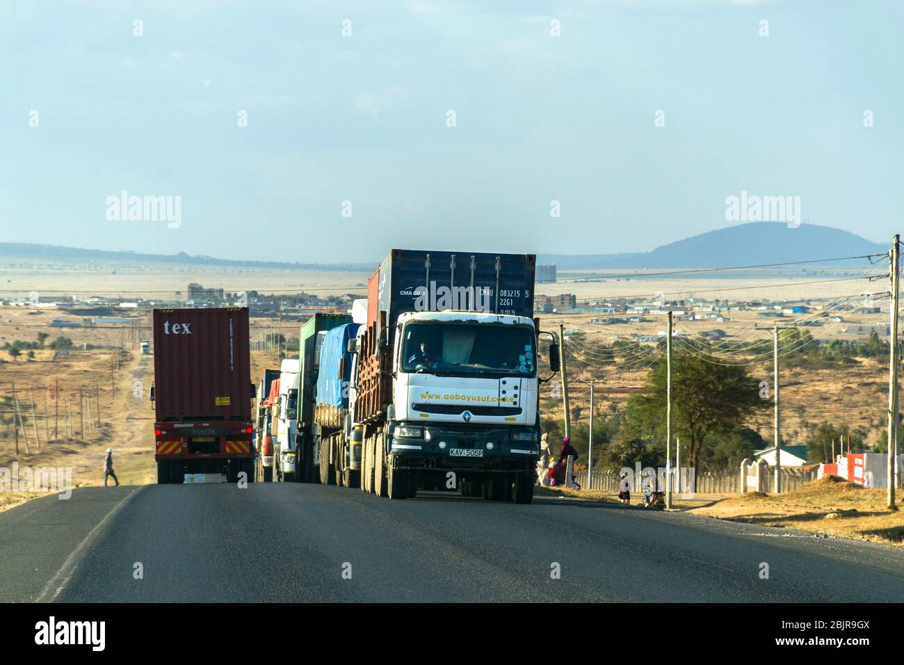 Lastwagen fahren einen Hügel hinauf und transportieren Waren auf der Mombasa Road, Kenia, Ostafrika Stockfoto