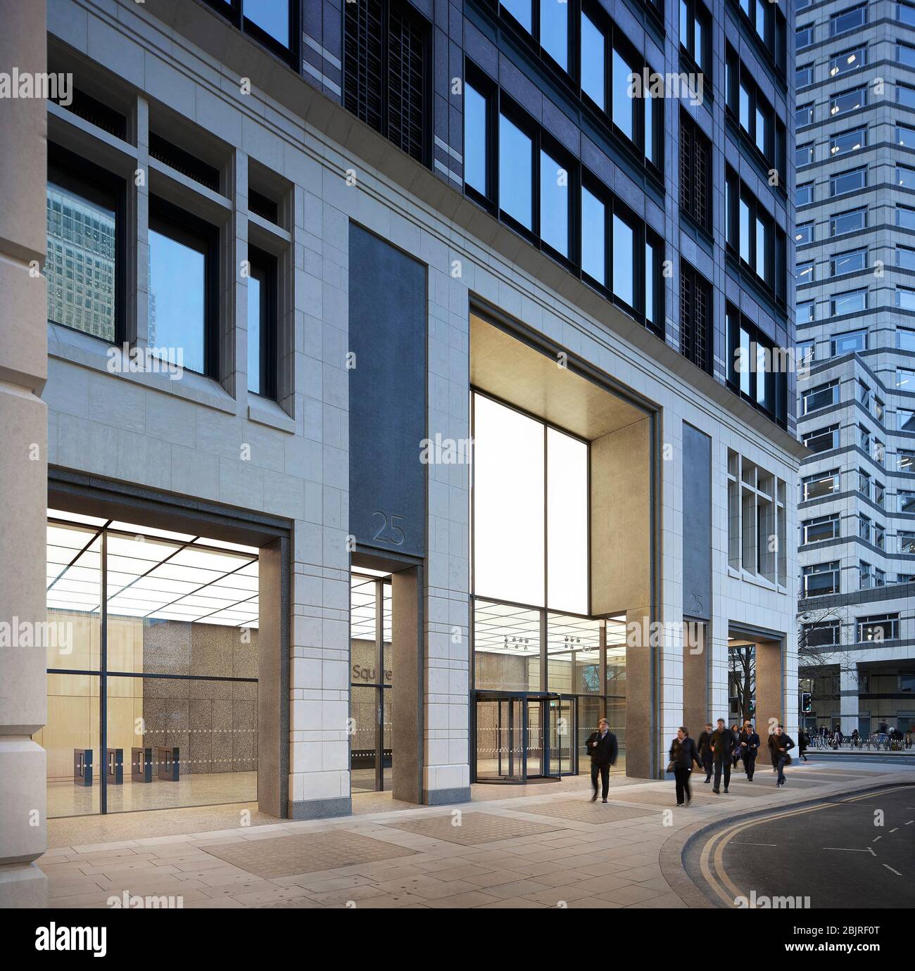 Empfangsbereich für Unternehmen mit beleuchteter Decke in der Dämmerung von außen. 25 Cabot Square, London, Großbritannien. Architekt: Carmody Groarke, 2019. Stockfoto