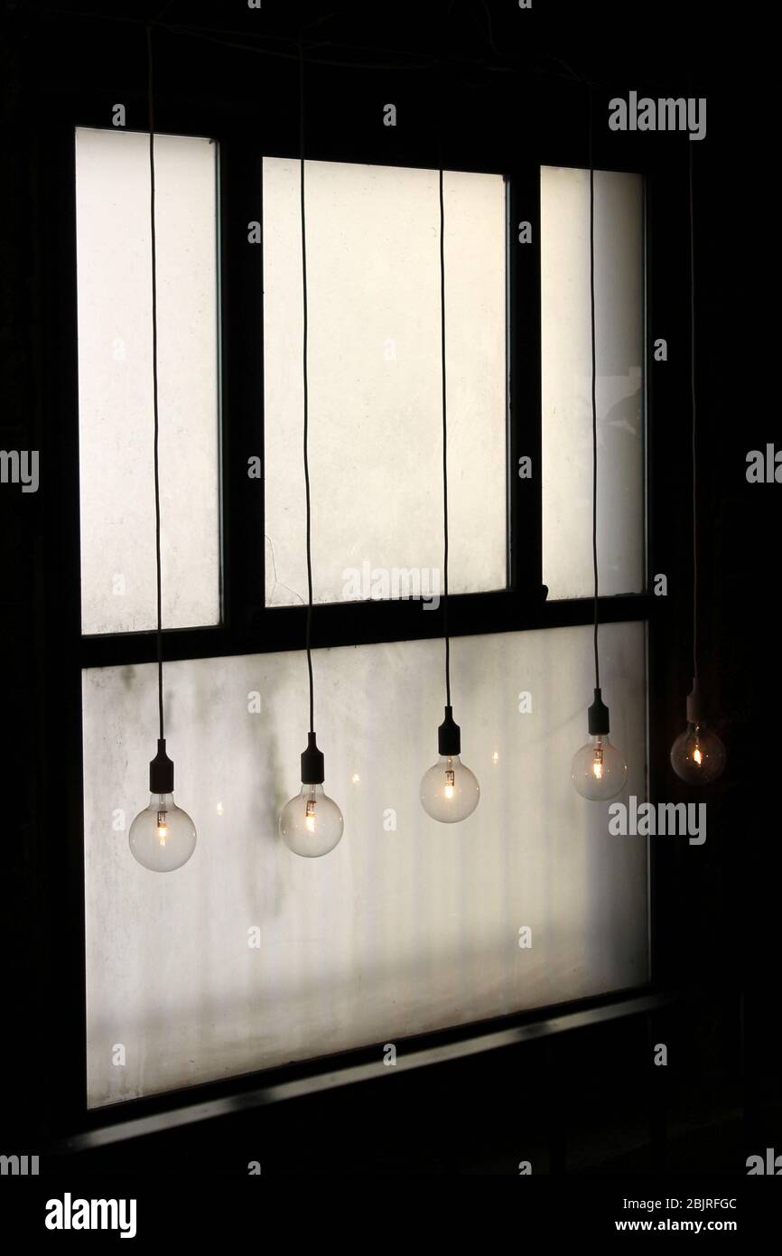 Glühbirnen hängen vor einem alten Fenster. Stockfoto