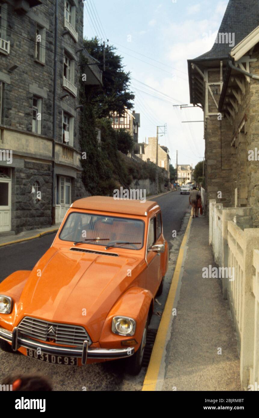 Ein orangenes Citroen Dyane Auto parkte vor einem traditionellen Haus in St Cast Le Guildo, Bretagne, Frankreich 1974. Stockfoto