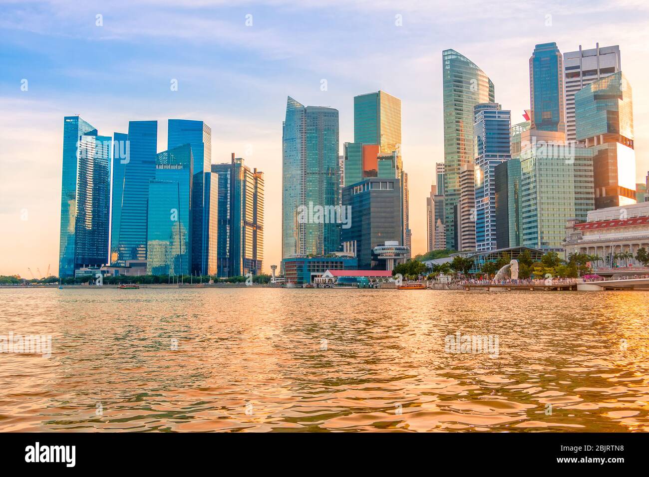 Abend Singapur. Wolkenkratzer am Ufer der Marina Bay. Die Sonne färbte das Wasser golden Stockfoto