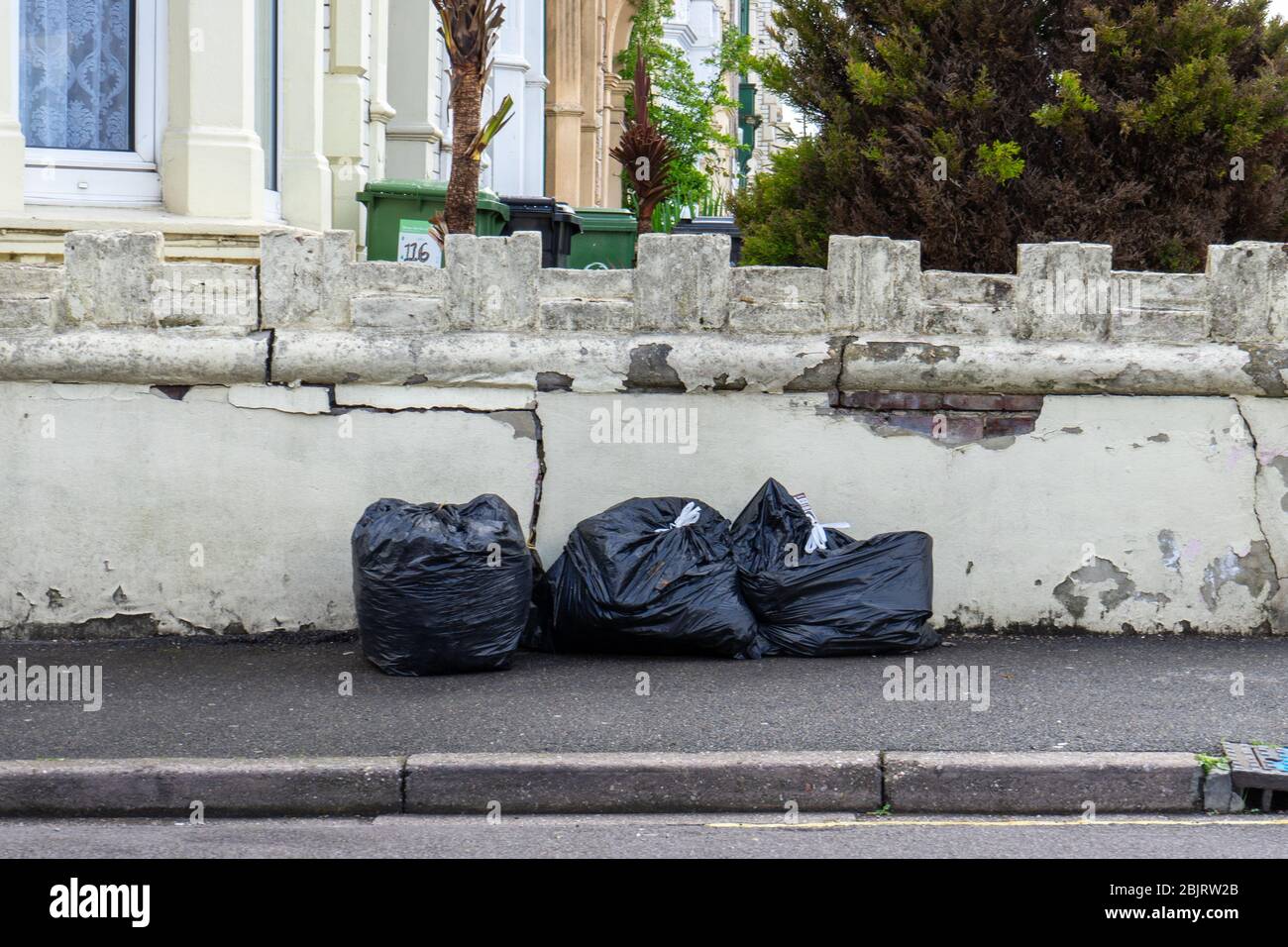 Schwarze Müllsäcke voller Müll auf einer Straße oder einem Bürgersteig Stockfoto