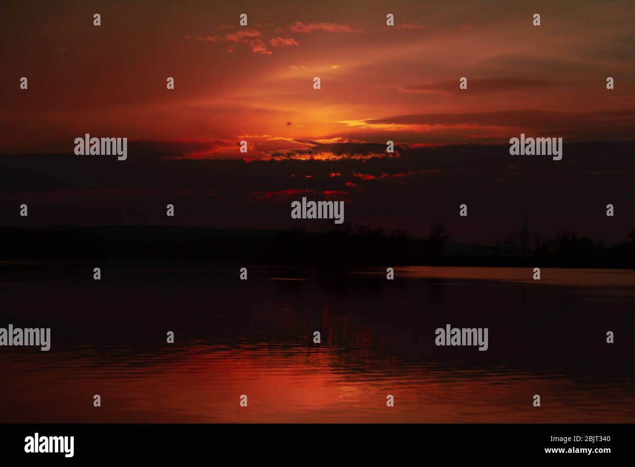 Sonnenuntergang über dem Fluss die Sonne versteckte hinter den Wolken einen blutigen Himmel in einer dunklen Ader Stockfoto