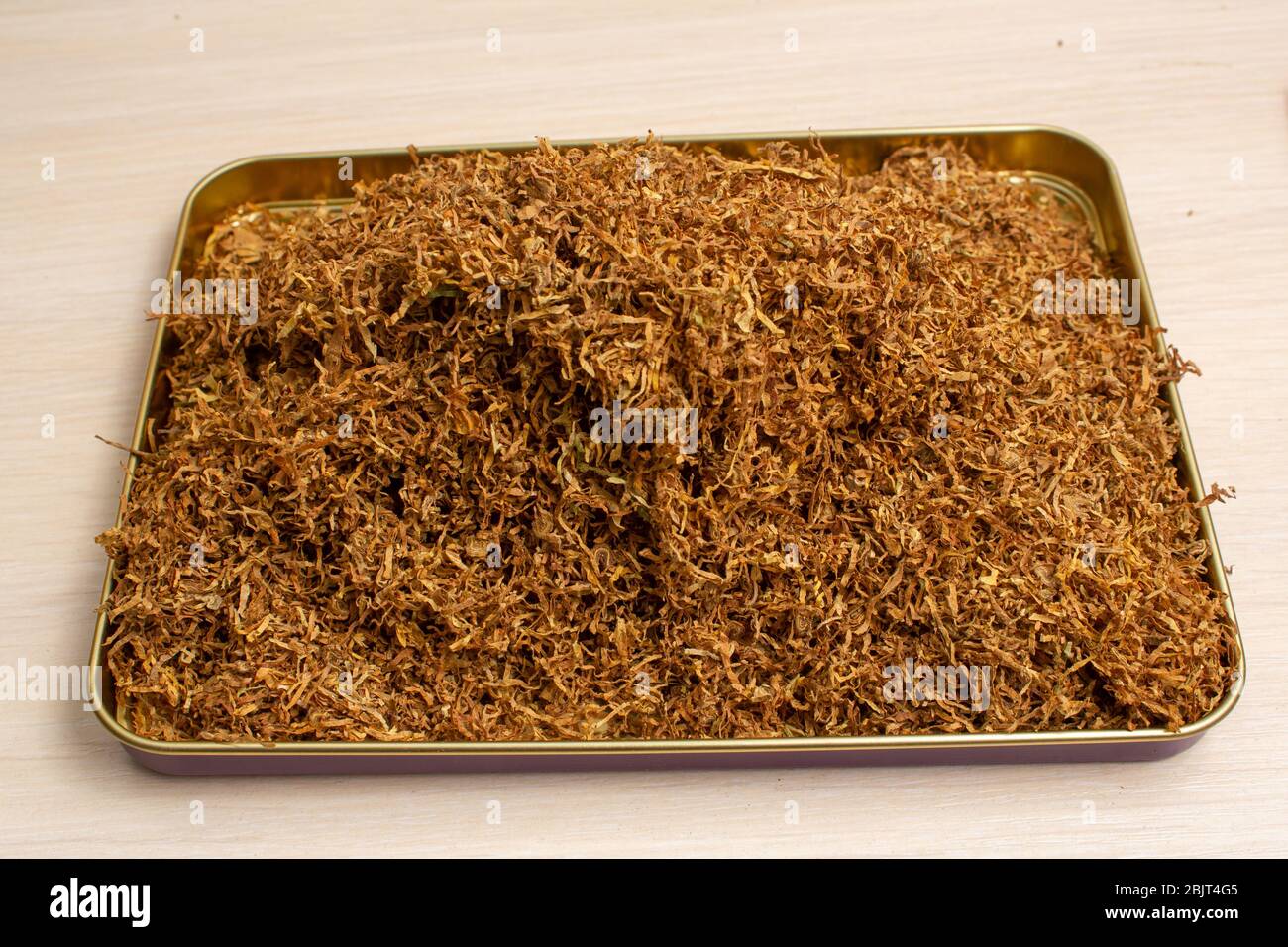 Dia Tabak in einem Eisenbehälter auf einem hellen Holz Stockfoto