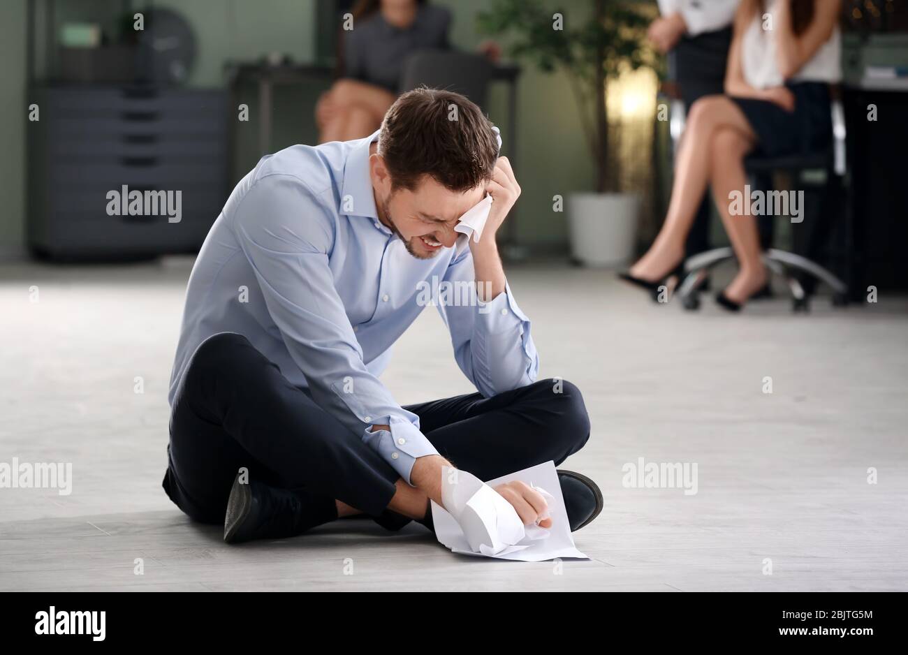 Junger Mann, der bei der Arbeit gemobbt wird Stockfoto