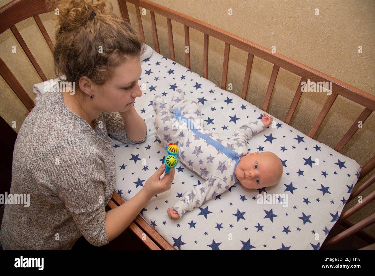 Mama zeigt seinem neugeborenen Kind, das in einer Krippe liegt, eine ...