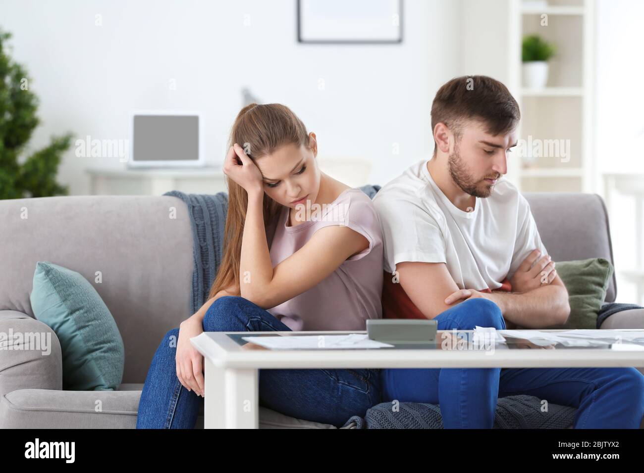 Unglückliches Paar in der Nähe des Tisches mit Rechnungen zu Hause. Geldprobleme in Beziehung Stockfoto