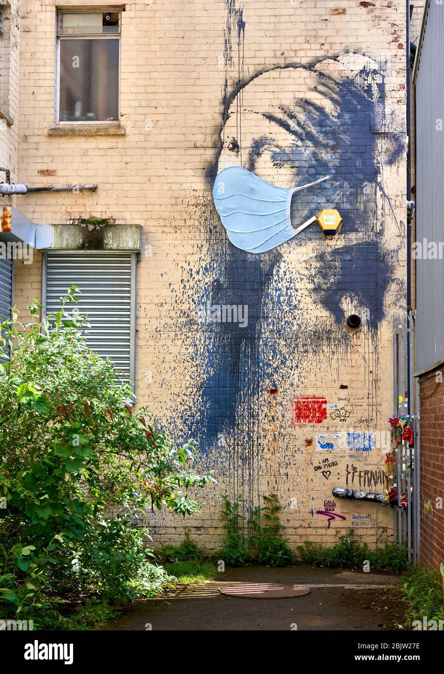Eine Gasse in Bristol UK mit Banksy's The Girl with the Pierced Eardum, die während der Coronavirus-Pandemie von 2020 eine Gesichtsmaske trägt Stockfoto