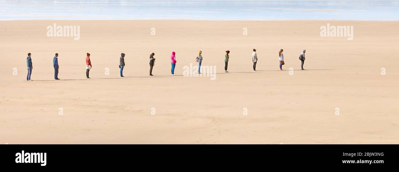 Junge Leute stellen sich zwei Meter auseinander, um während der Coronavirus-Pandemie 2020 - Großbritannien - an einem Strand soziale Distanz zu bewahren Stockfoto