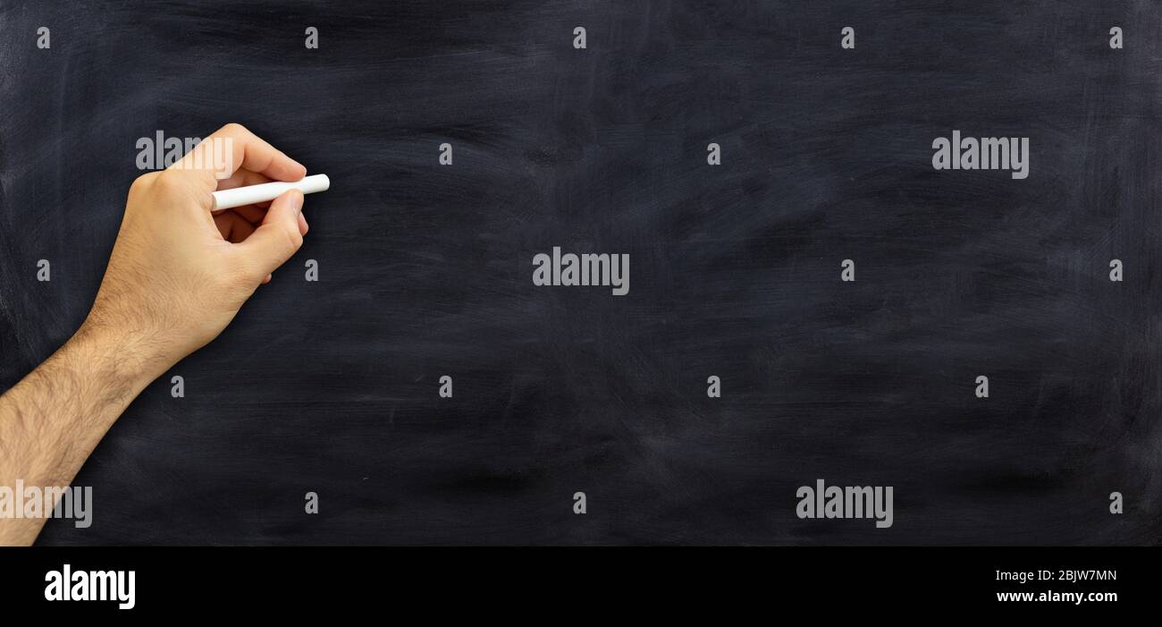 Linke Hand hält eine Kreide isoliert auf schwarzem Hintergrund. Linkshänder gegen eine Tafel, Kopierer, Banner Stockfoto