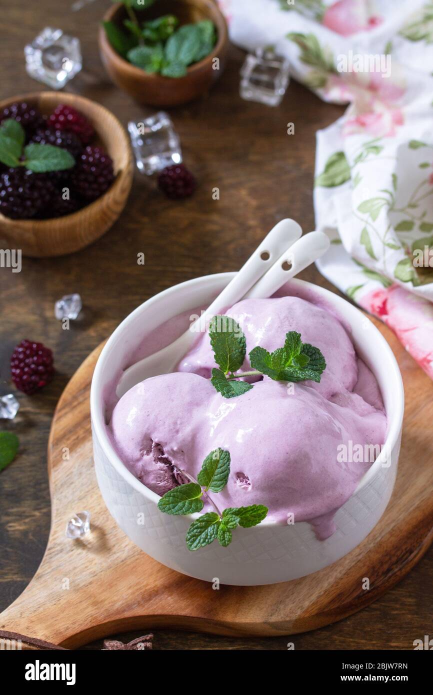 Hausgemachte Bio-Eiscreme mit Minze. BlackBerry Eis in weißer Schüssel auf einem rustikalen Tisch. Stockfoto