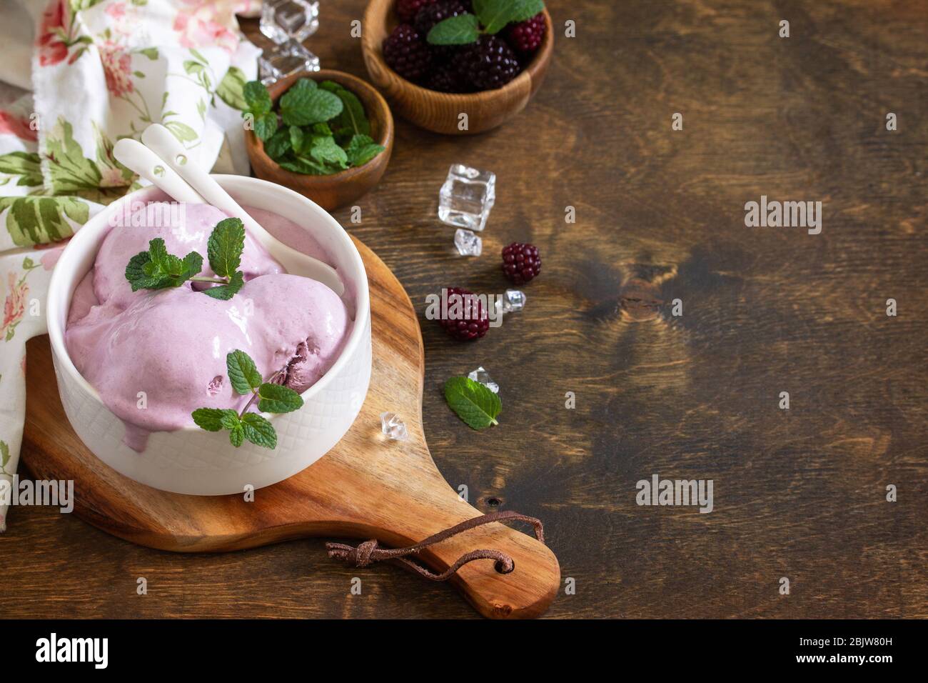 Hausgemachte Bio-Eiscreme mit Minze. BlackBerry Eis in weißer Schüssel auf einem rustikalen Tisch. Kopierbereich. Stockfoto