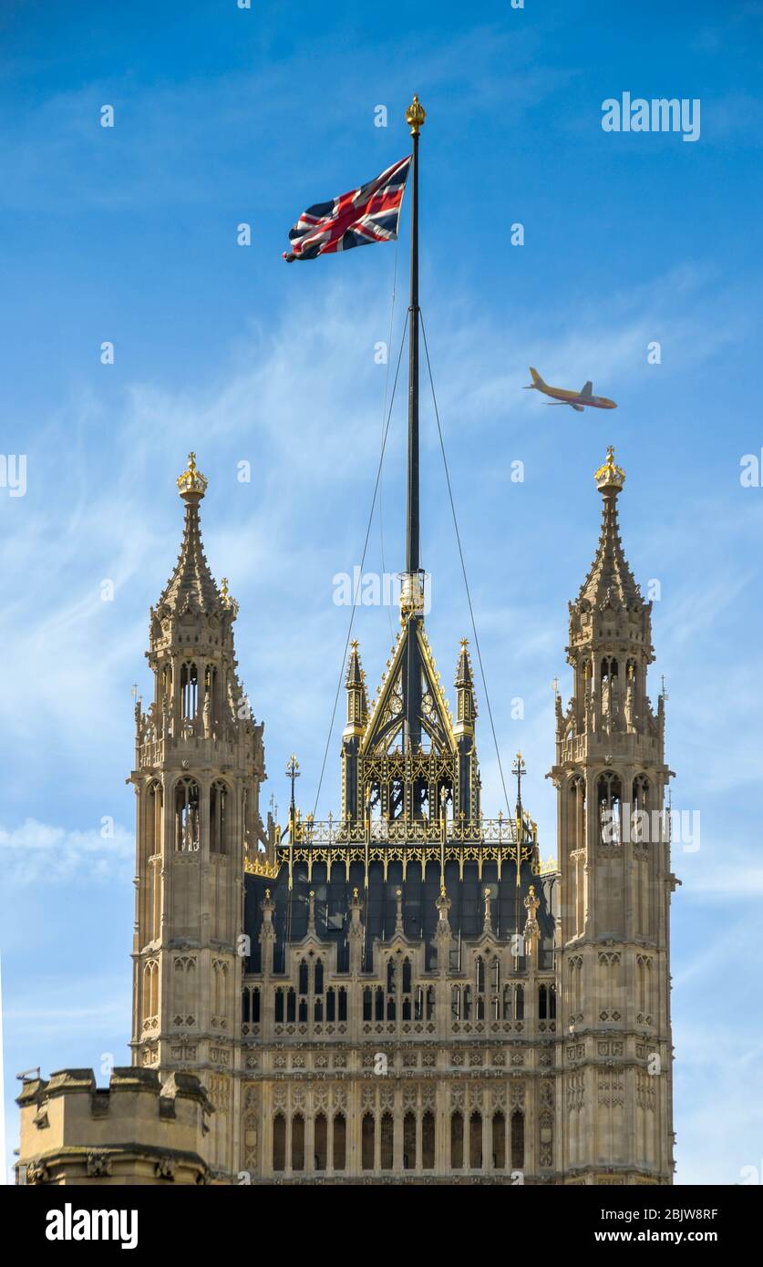 LONDON, ENGLAND - JUNI 2018: Der Victoria Tower im Palace of Westminster mit der Union Jack Flagge und einem vorbeifliegenden Jet Stockfoto