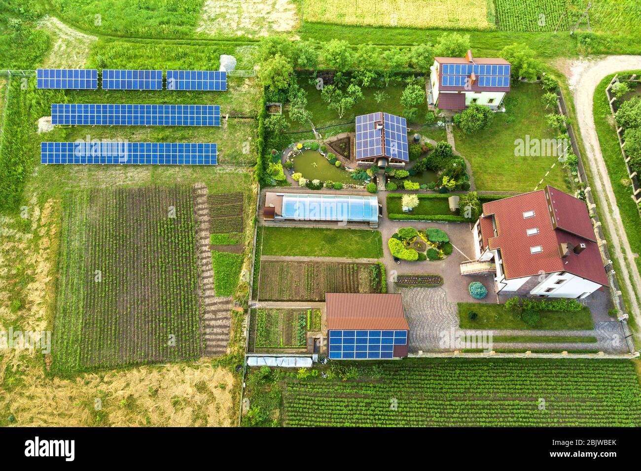 Luftbild eines Privathauses im Sommer mit blauen Sonnenfoto-Voltaikfeldern auf dem Dach und im Hof. Stockfoto