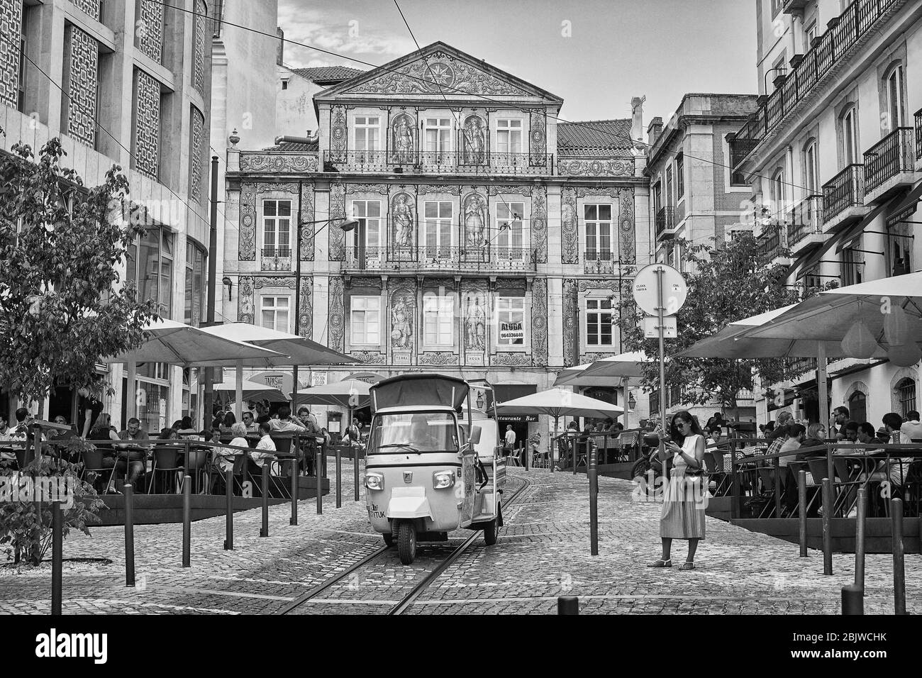 Ein Tuk-Tuk fährt durch einen plaza-Bereich der Altstadt von Lissabon, Portugal mit einer schönen Keramikfassade im Hintergrund Stockfoto