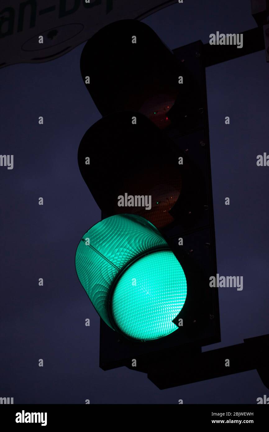 Grüne Ampel gegen den Himmel in der Dämmerung. An einer Ampel leuchtet abends die grüne Ampel. Stockfoto