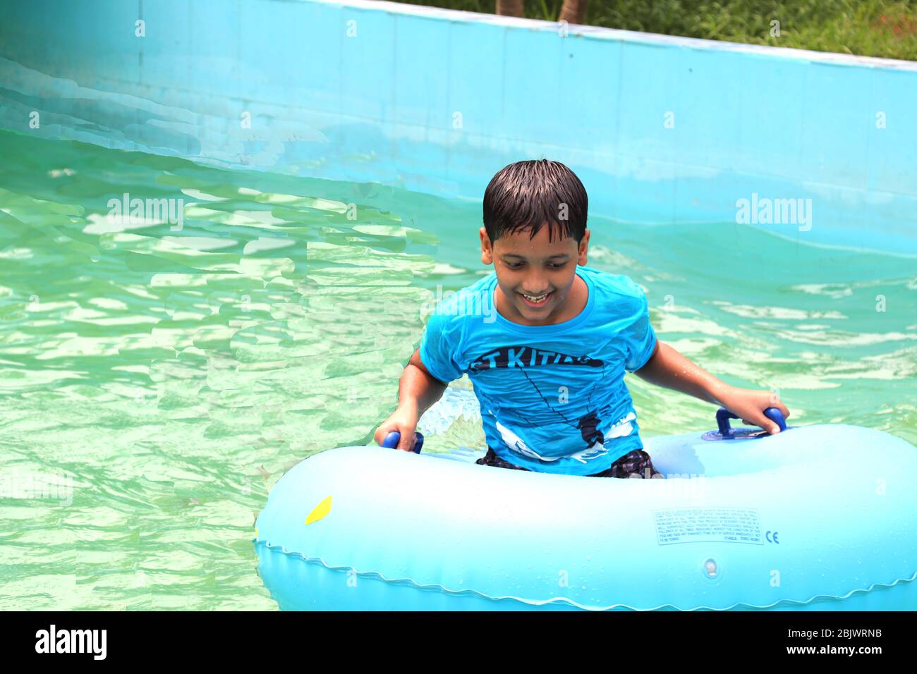 Ein Schuljunge genießt am Schwimmbad Wasser allein in seiner Ferienzeit, Spaß Schwimmen Moment in der Kindheit Stockfoto