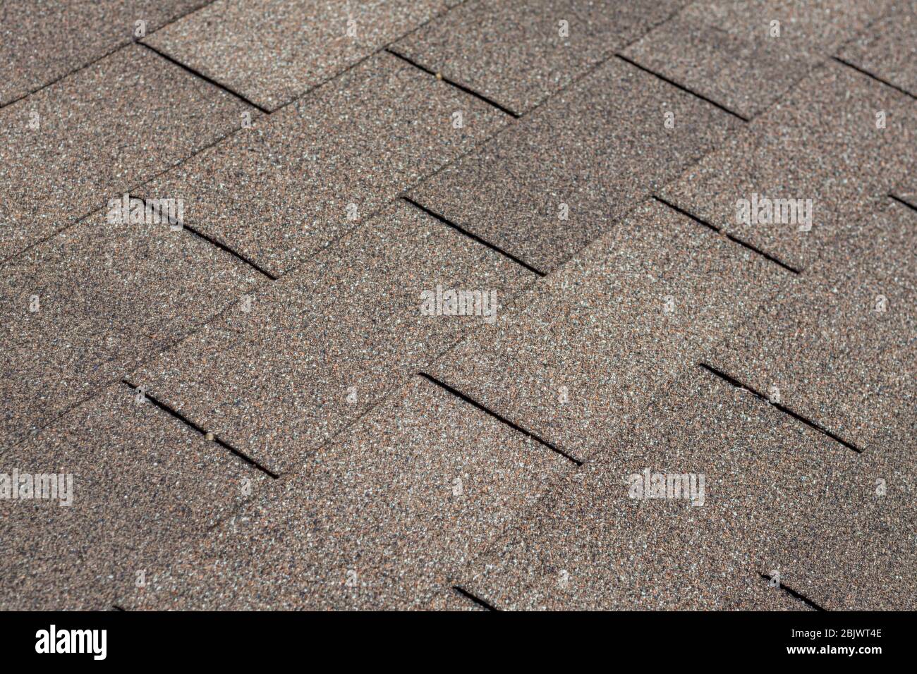 Ein Hintergrundbild von Schindeln auf einem Hausdach, das ihre Textur, Muster und braune Farbe zeigt. Stockfoto