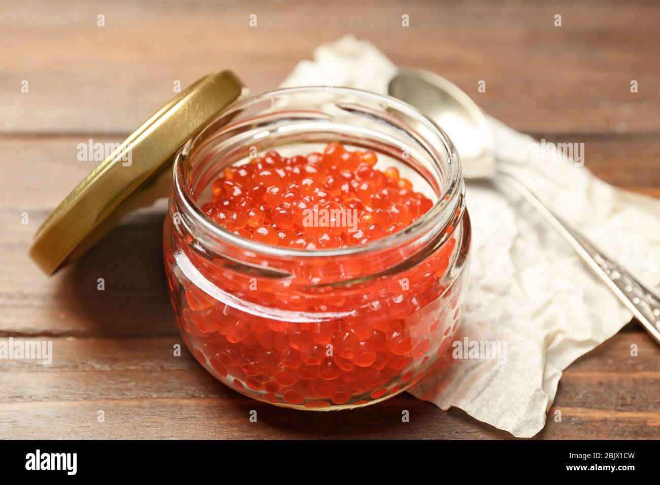 Glas mit rotem Kaviar auf Holztisch Stockfoto