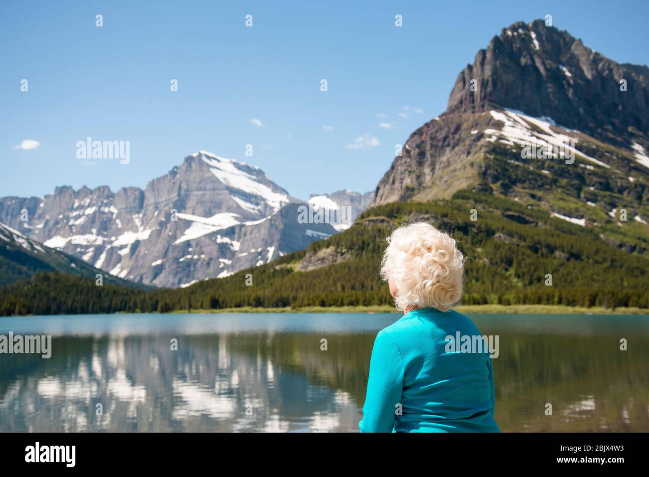 Ältere Frau, die von der Kamera weg auf die Berglandschaft Montana schaut. 70 Jahre alt Blonde Hair Glacier National Park Kopie Raum szenisches Ziel. Stockfoto