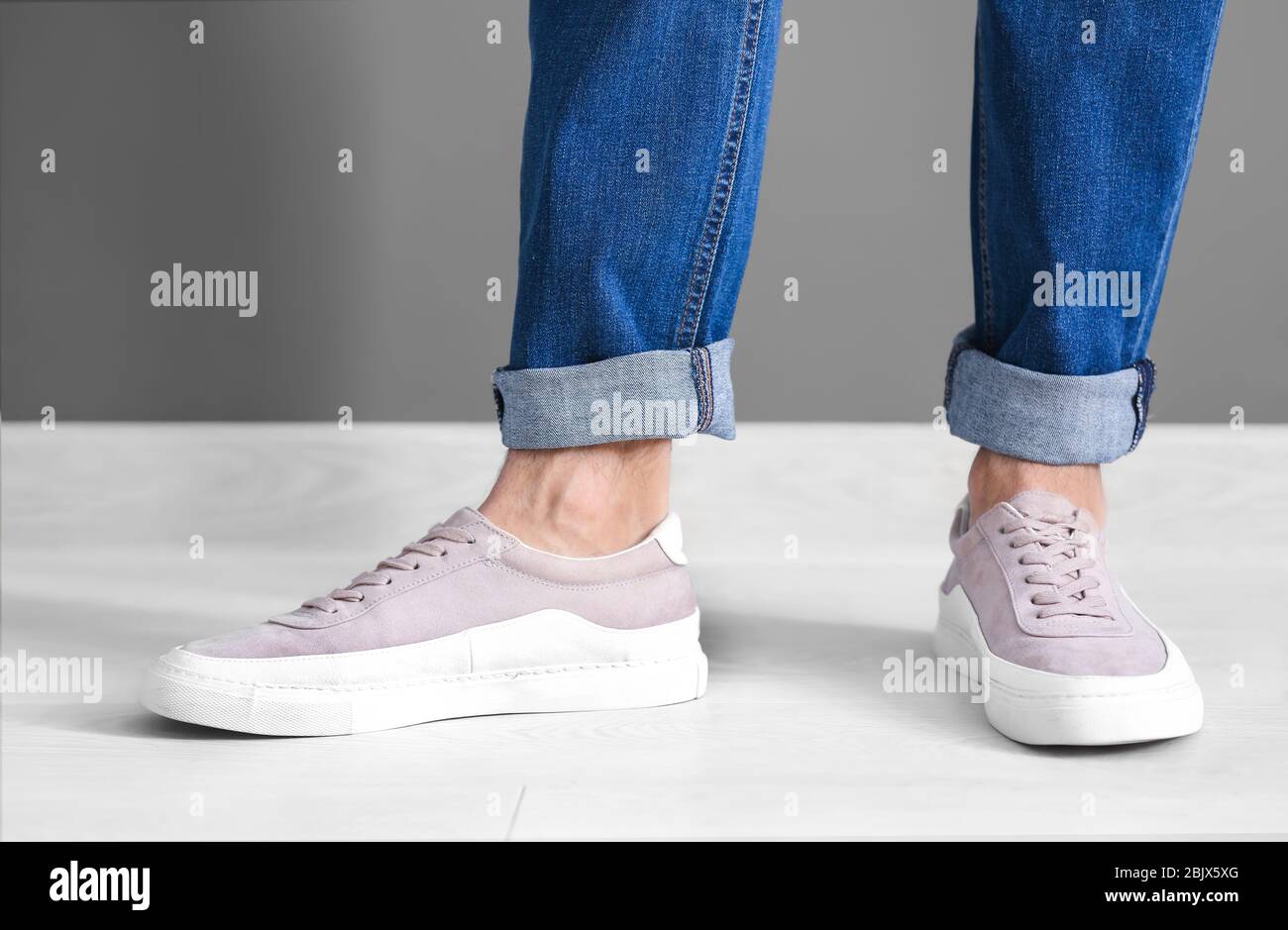 Mann in lässigen Schuhen nahe grauer Wand Stockfoto
