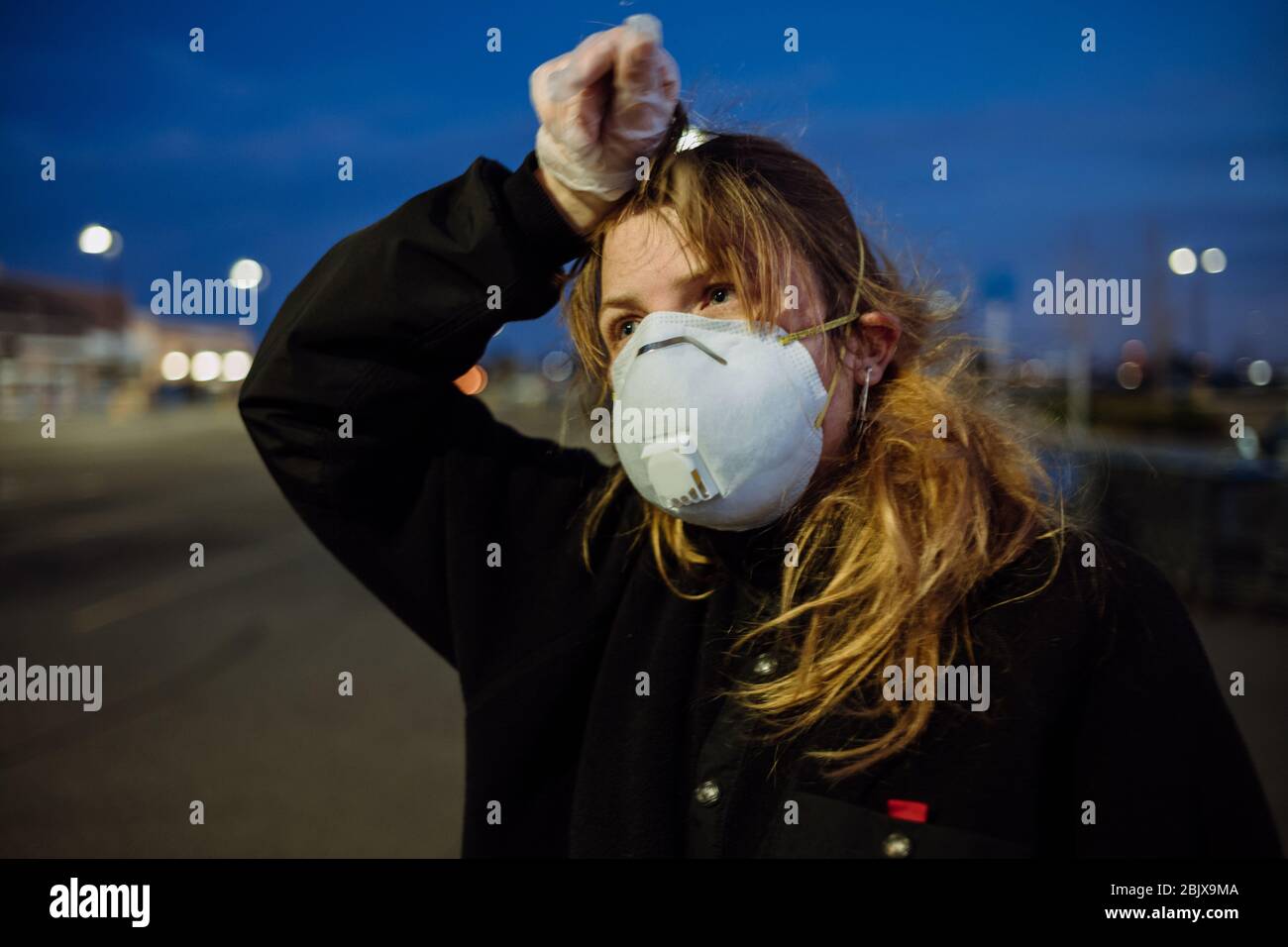 Eine Frau, die während der weltweiten Pandemie Covid-19 eine PSA-Gesichtsmaske und Handschuhe vor einem Lebensmittelgeschäft trägt. Stockfoto