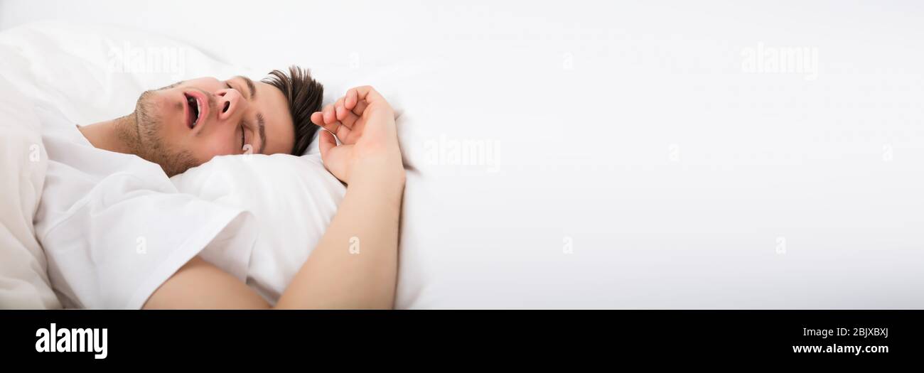 Blick auf Müde junge Mann Schnarchen während Tief schlafen im Bett Stockfoto