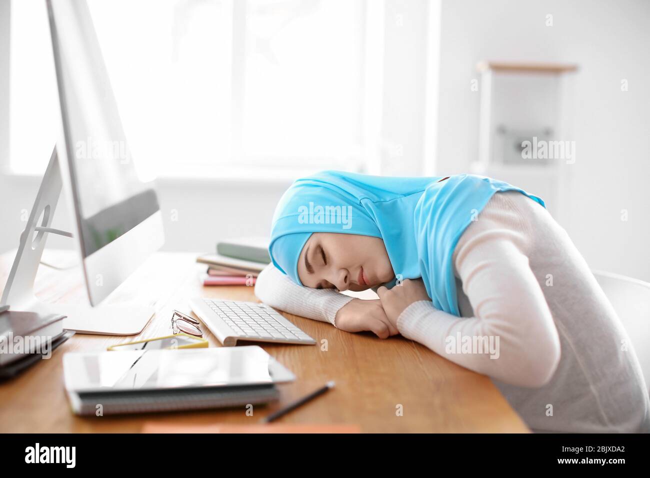 Muslimische Schüler in traditioneller Kleidung schlafen am Tisch drinnen Stockfoto