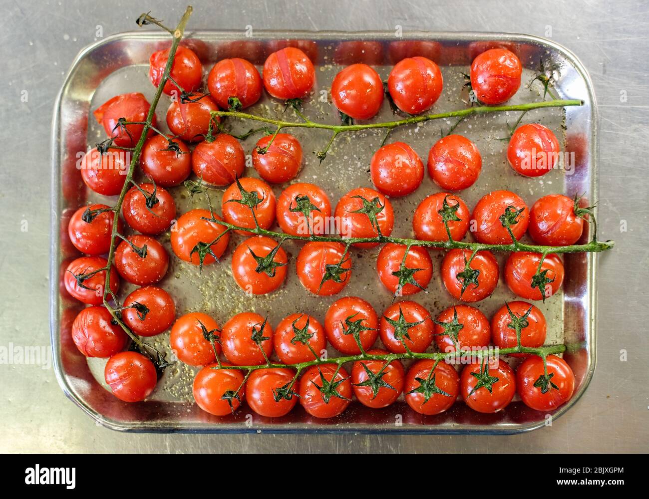 Im Ofen gebackene Kirschtomaten in Backblech in der Restaurantküche. Draufsicht, flaches Lay Stockfoto