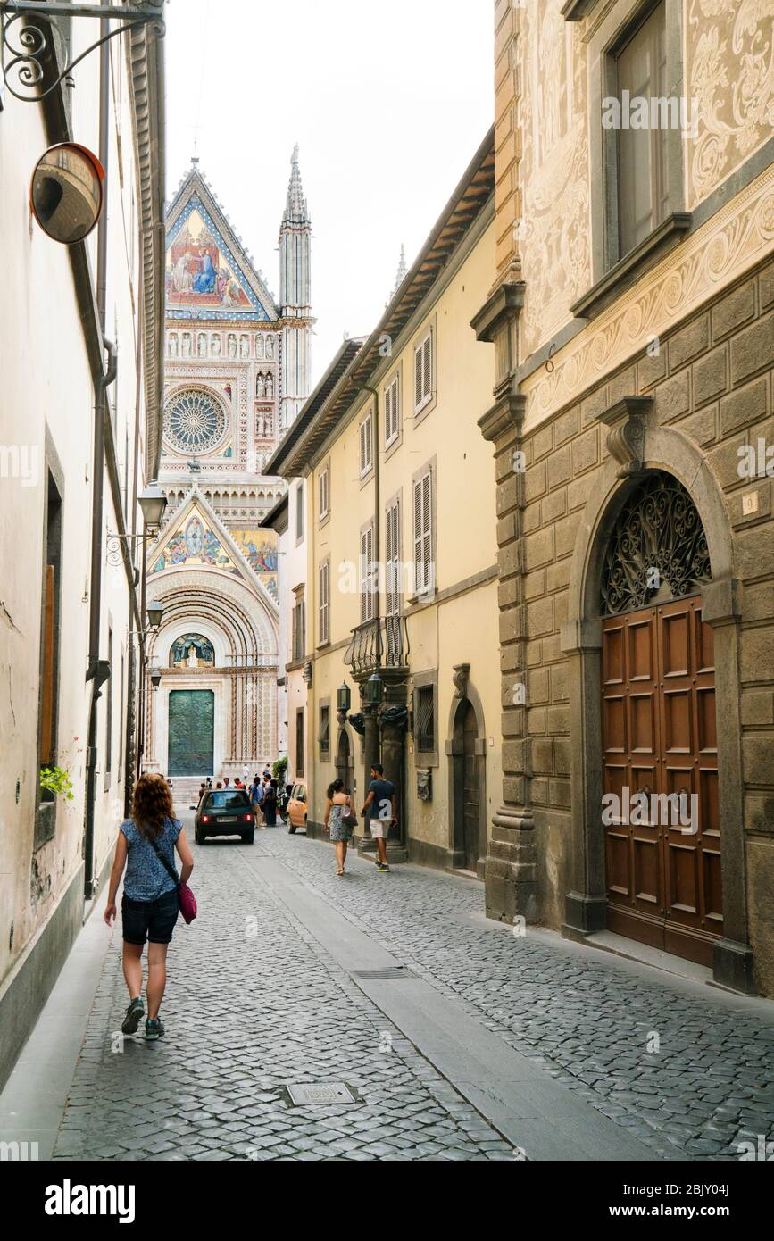 Touristen gehen die schmale Straße hinunter, die zum Dom führt, Italiens kühnster und beeindruckendster romanischer gotischer Dom aus dem Jahr 1290, der aus dem Jahr 1945 stammt Stockfoto